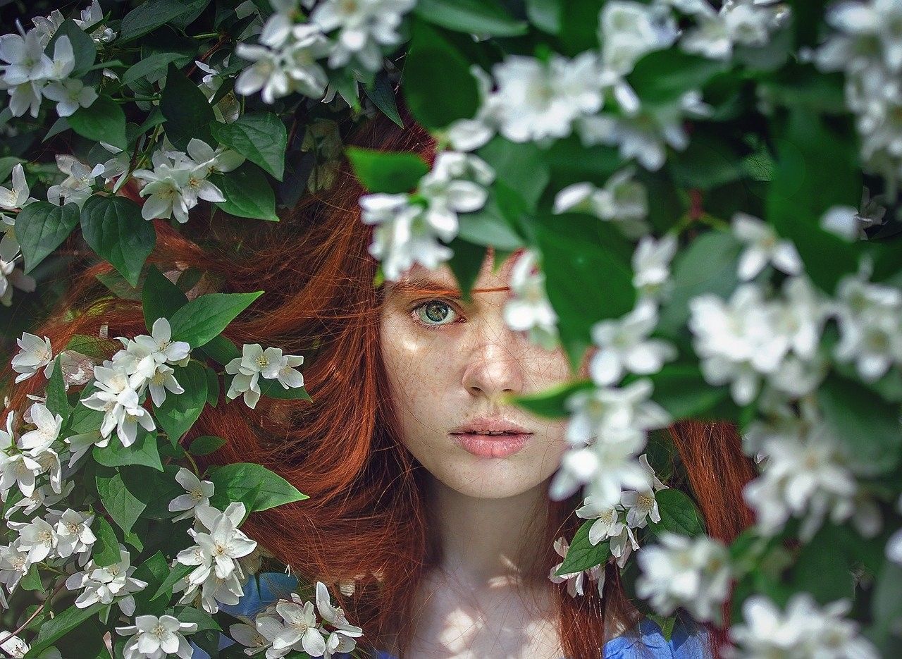 Pretty girl with red hair in flowers